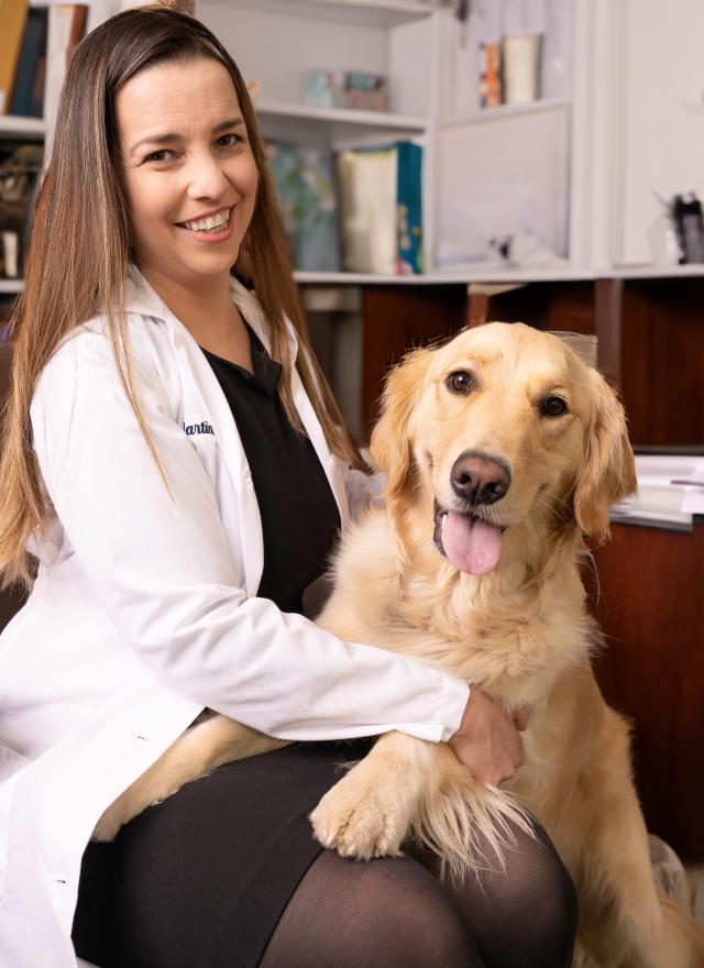 Women in a lab coat petting a golden retriever