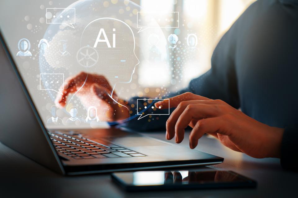 stock photo of hands displayed over a laptop with the text AI 